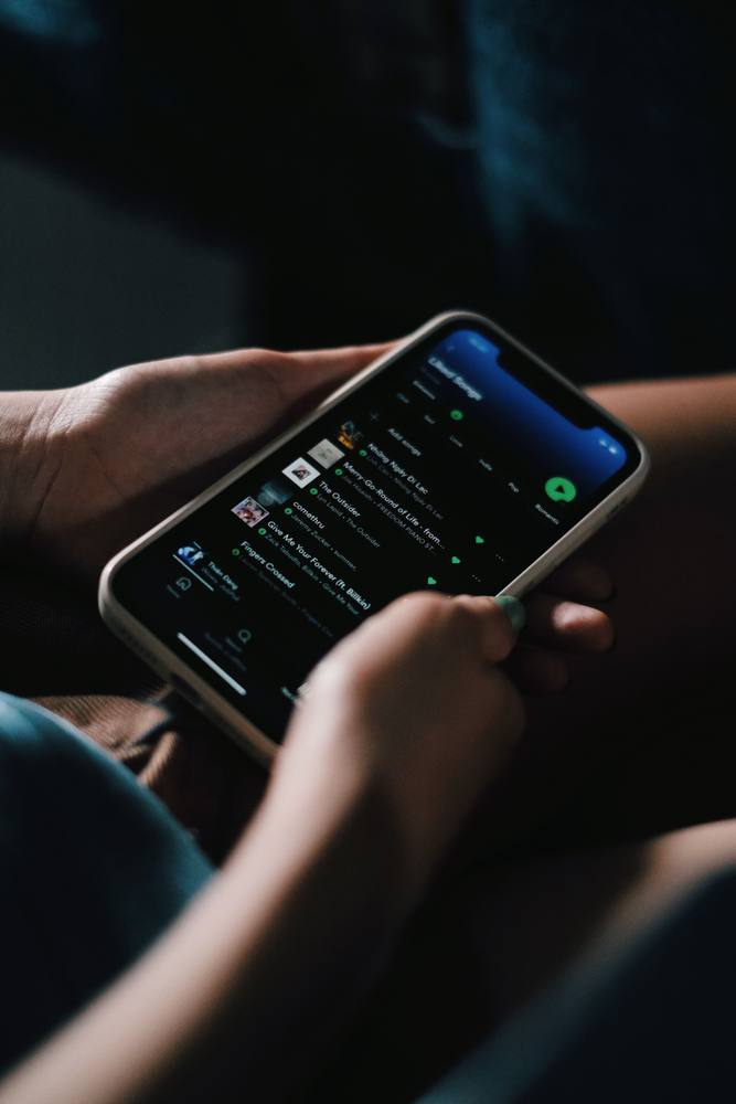 Hands holding a phone with Spotify open