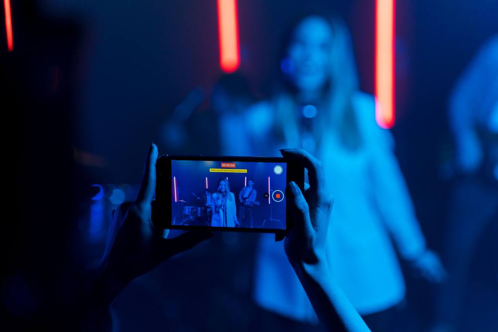 Fan filming a singer on stage with a phone