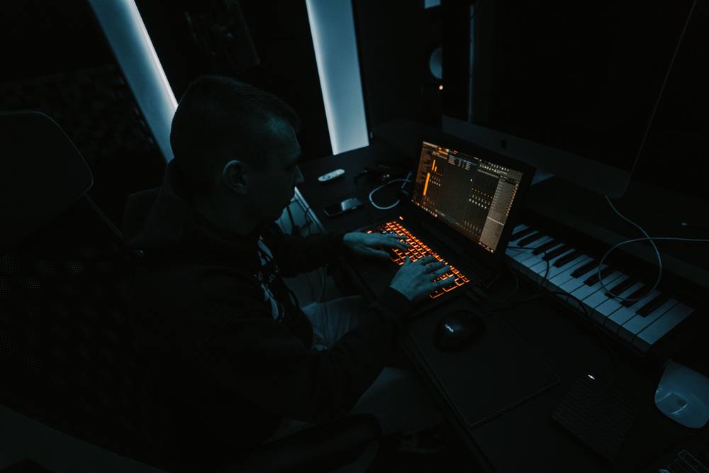 Producer working at a laptop and keyboard in a studio