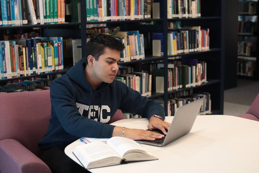 Student learning on a laptop in a library